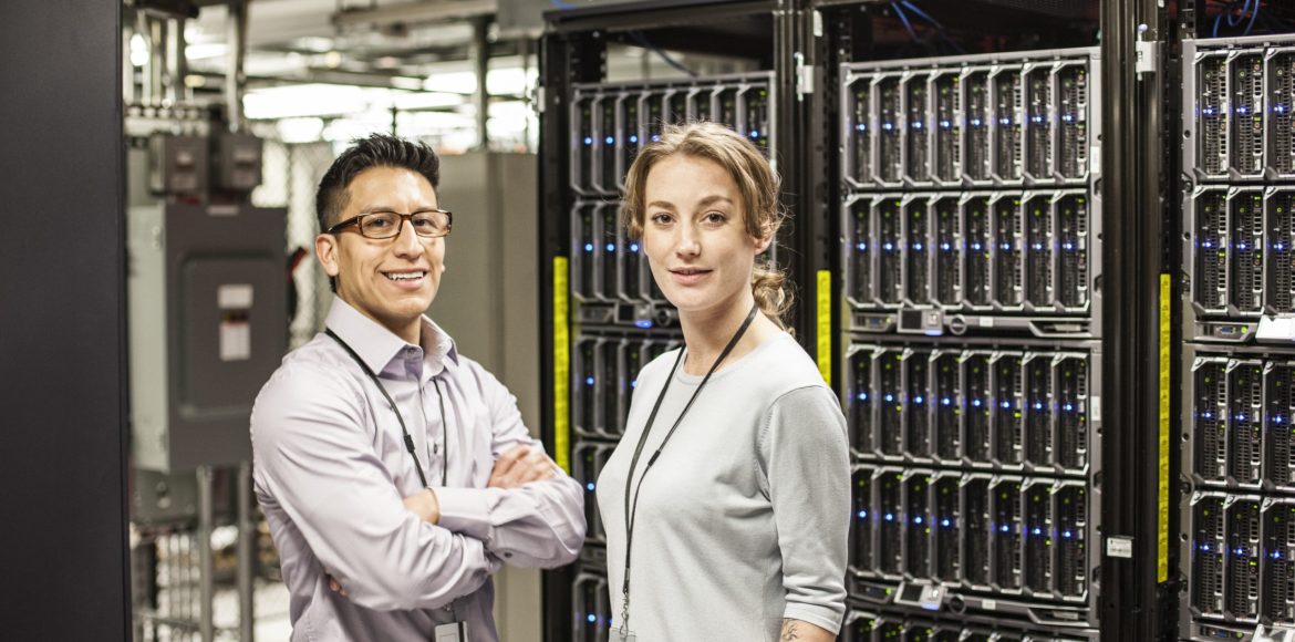 Caucasian man and woman technicians in a large computer server farm.