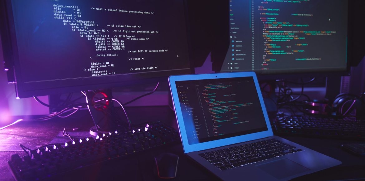 Background image of various computer equipment with programming code on screens on table in dark room, cyber security concept, copy space