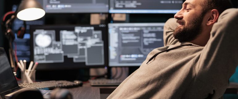 Smiling relaxed coder sitting laid back on chair Smiling relaxed coder sitting laid back on chair, feeling pleased about software development work in office. Enjoying server programming success late at night, server code html script.