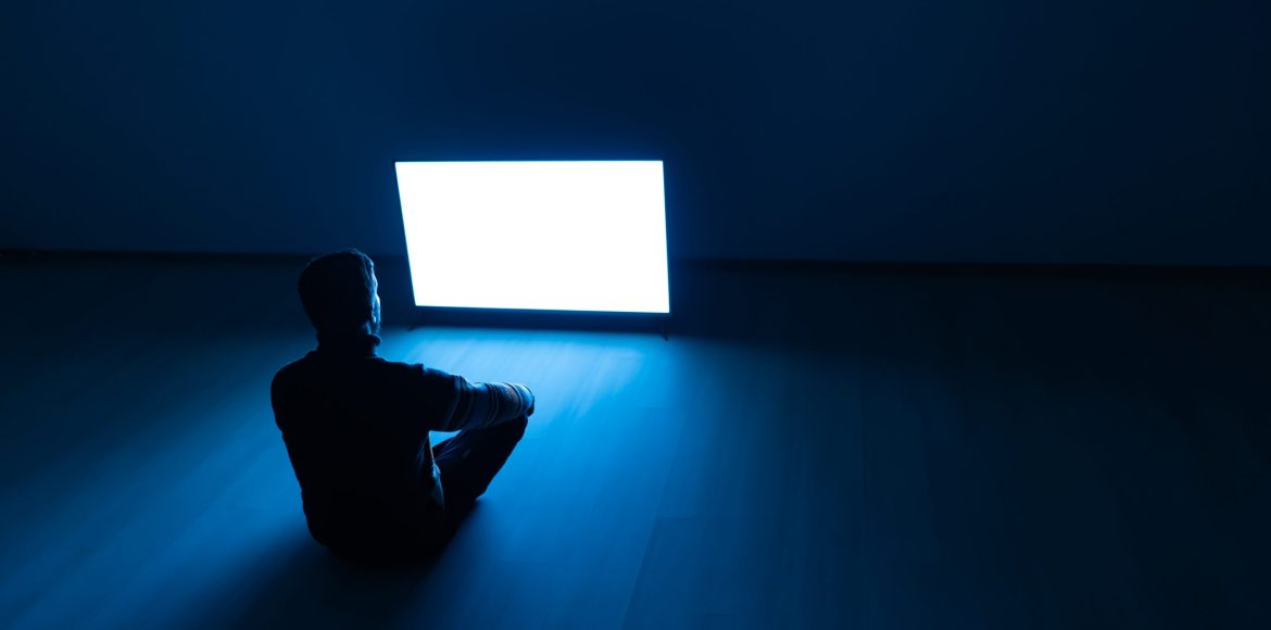 The man sitting on the floor in front of a white screen