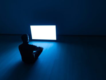 The man sitting on the floor in front of a white screen