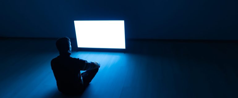 The man sitting on the floor in front of a white screen